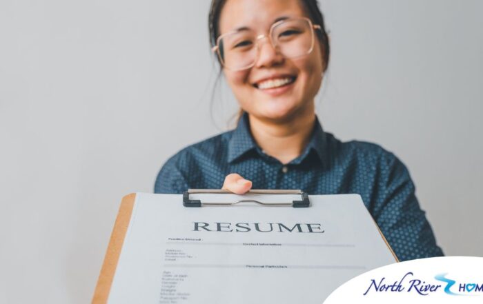 A woman happily hands in a resume, representing a successfully written caregiver resume.